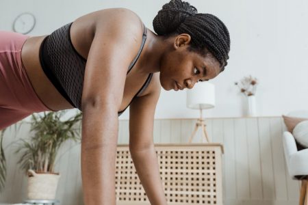 Woman with braided hair doing push-ups indoors, focusing on fitness and strength.